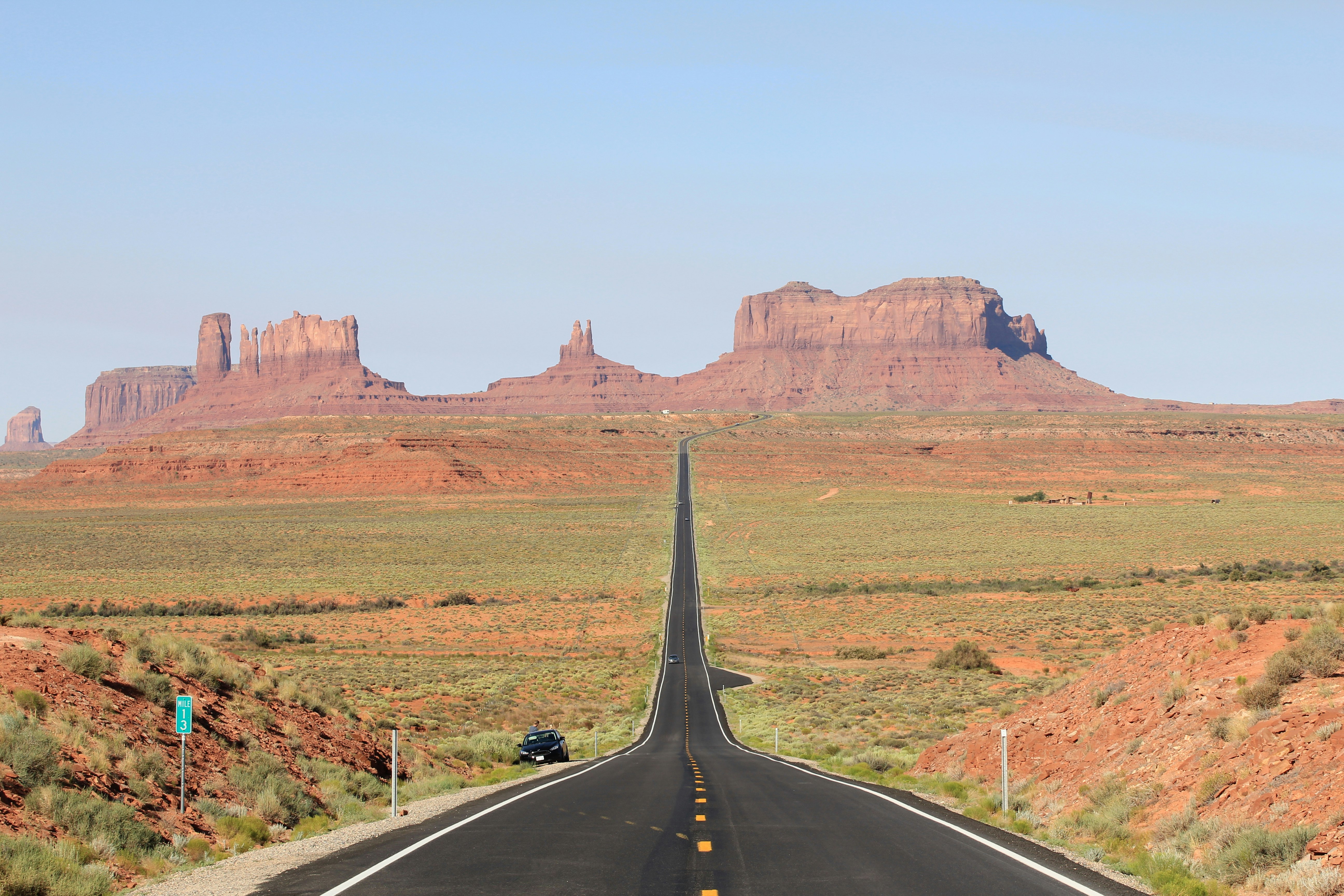 gray asphalt road between green grass field during daytime